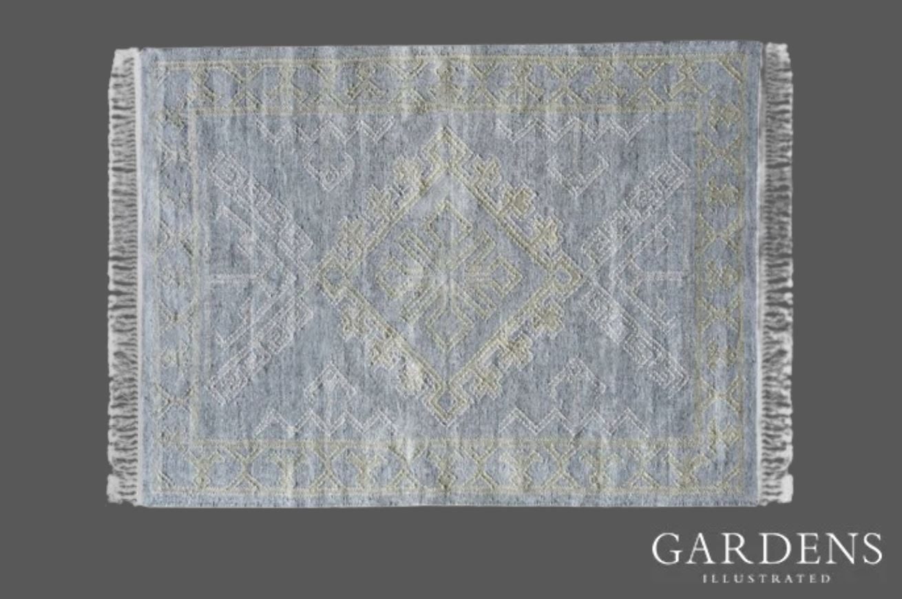 Andrew Martin Mara pale blue woven rug on a grey background