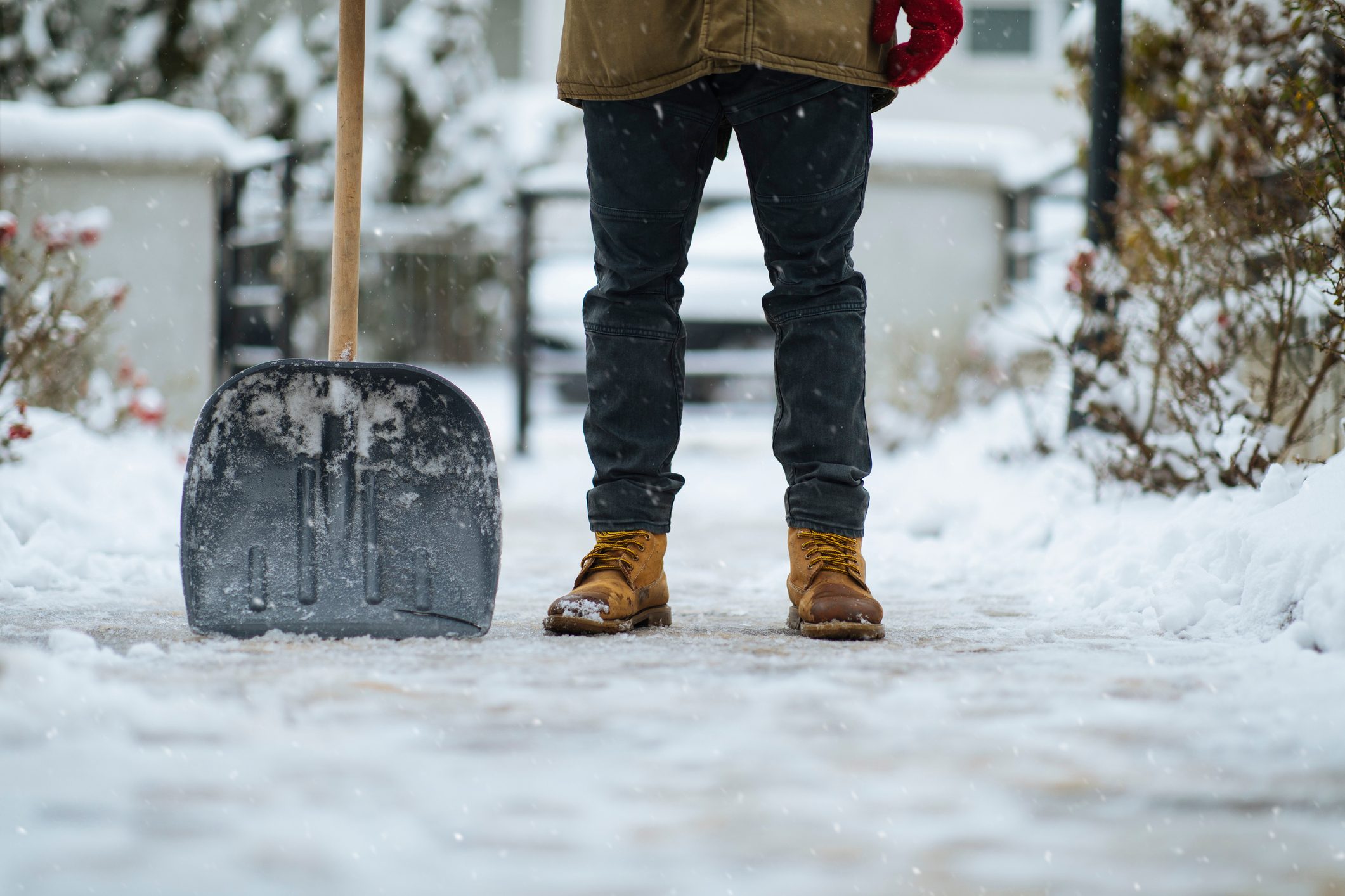Shovel and boots of a man after cleaning path from snow in a garden. Credit: mihailomilovanovic via Getty