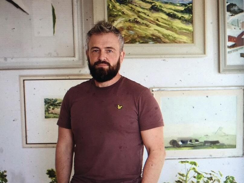 Man stood in front of a wall with hanging pictures