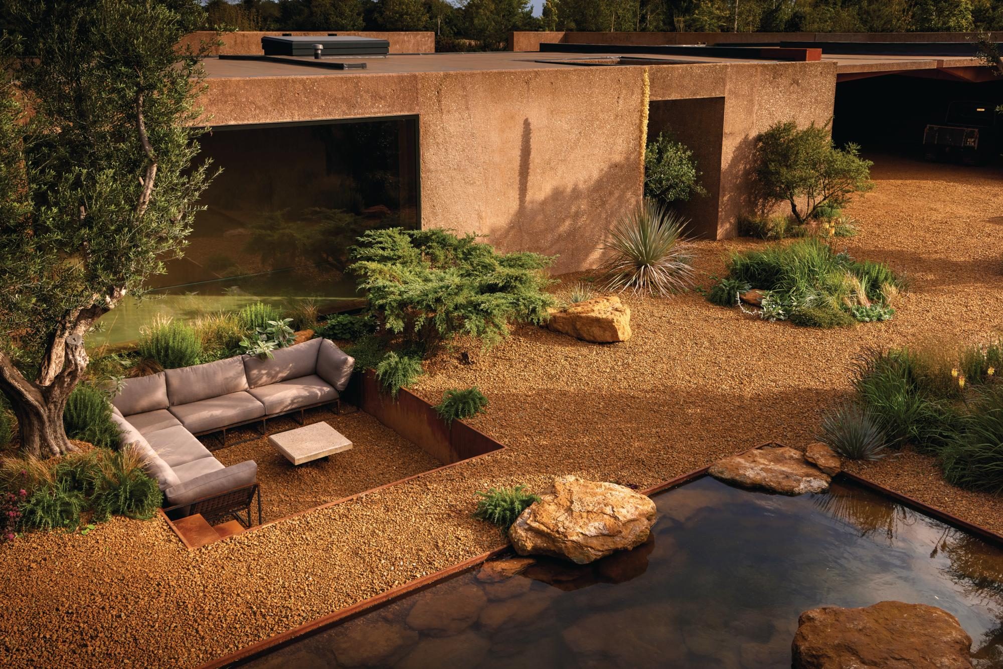 A gravel garden with a sunken seating area and grasses