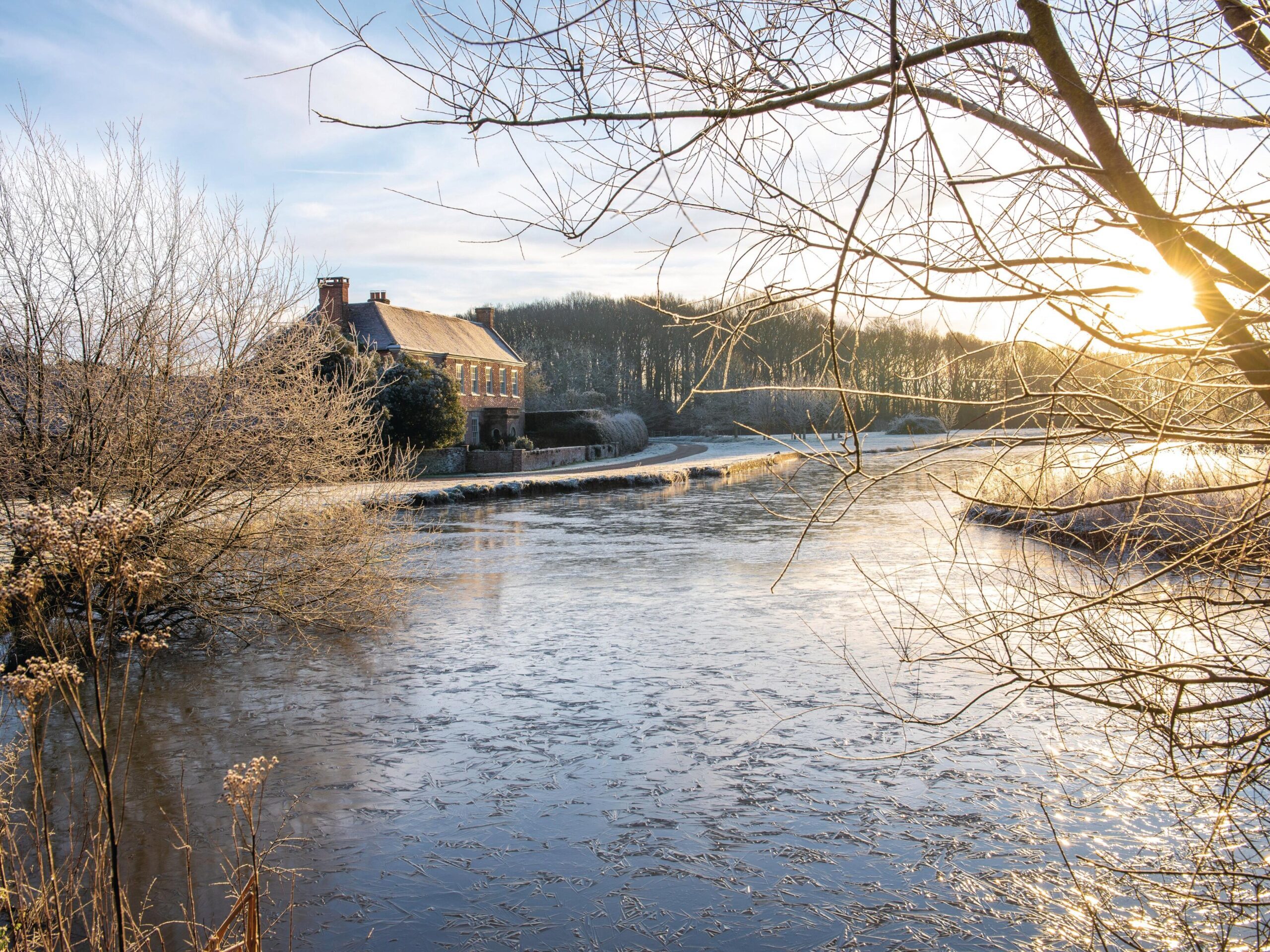 Farmhouse across pond in winter