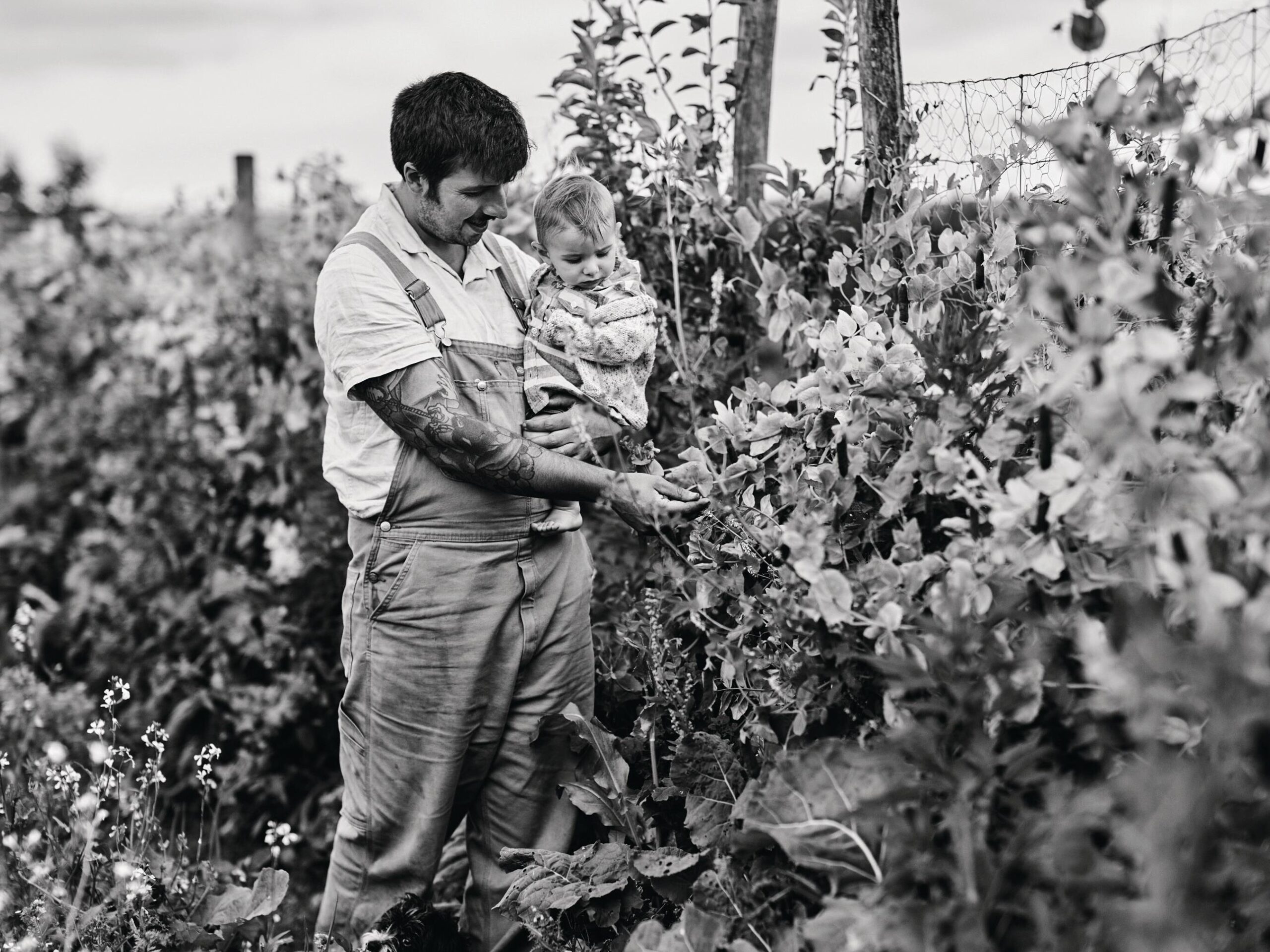 Man holding a baby in a field ©Andrew Montgomery