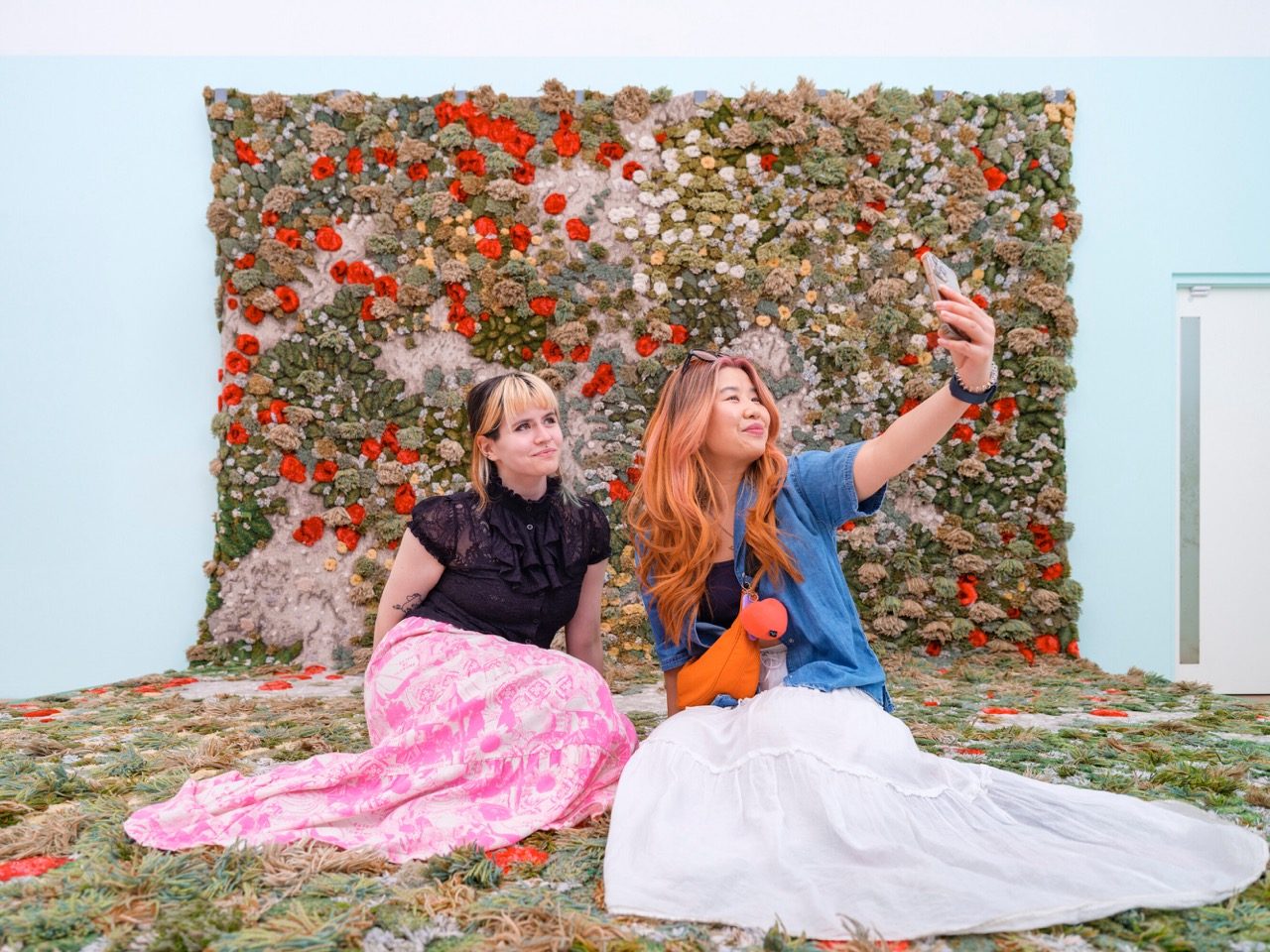 Two people sat in front of a flower wall exhibit